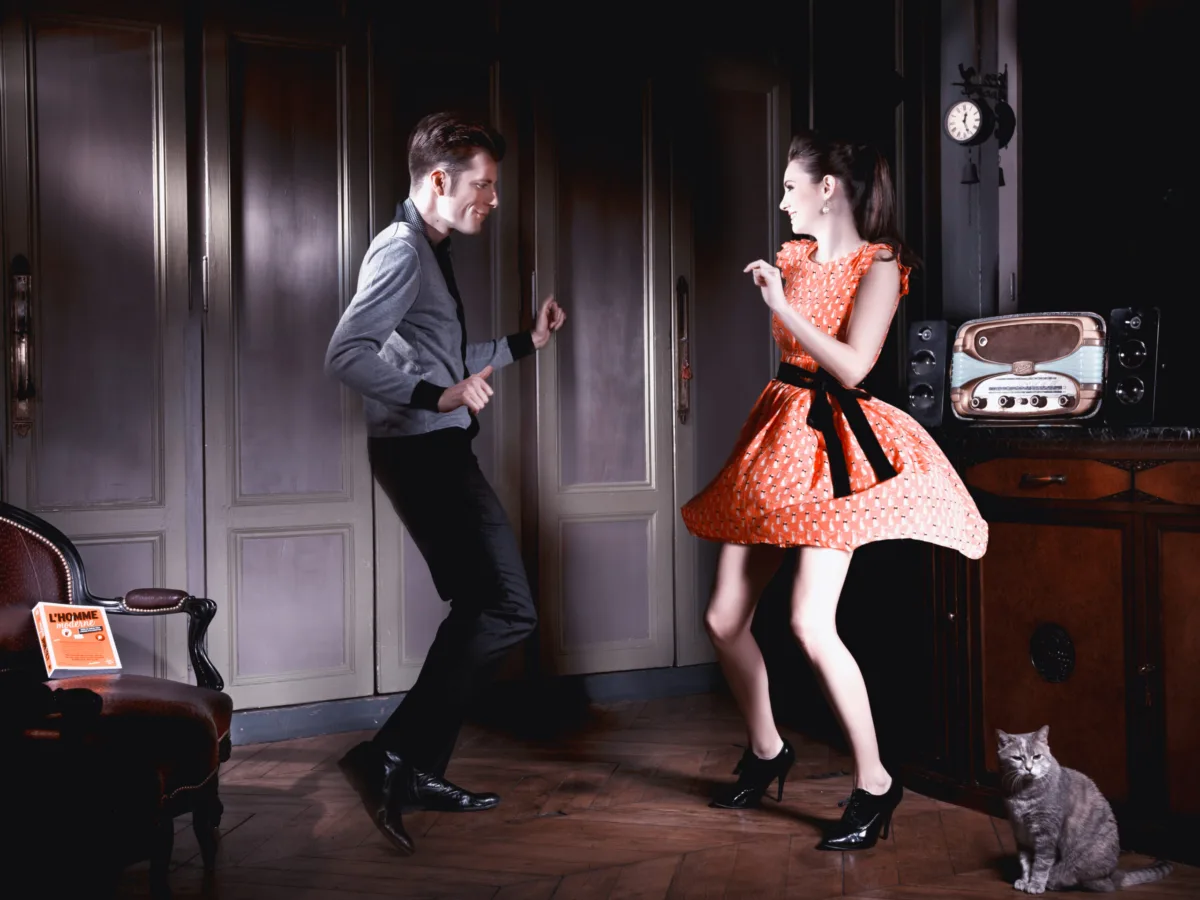 Staged interior: a couple dances in a panelled room, a cat watching
